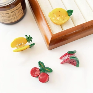 Macro shot of fruit-shaped mini hair claws including watermelon, cherry, and lemon designs