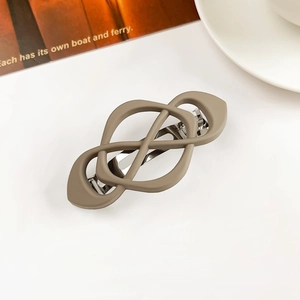 Close-up of matte taupe geometric hair clip with cross design and metal spring fastener