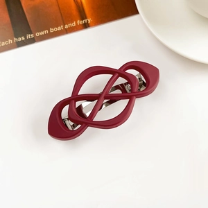 Detail of dark red matte hair clip with infinity knot design and silver metal spring