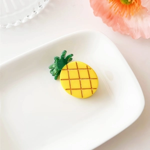 Detailed view of a yellow pineapple hair claw clip made of glossy acetate resin material