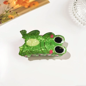 Detailed macro shot of a cute green frog hair claw clip made of glossy marbled acetate material
