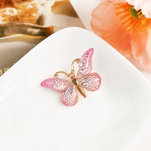 Détail d'une pince papillon dégradé rose avec des ailes dorées texturées