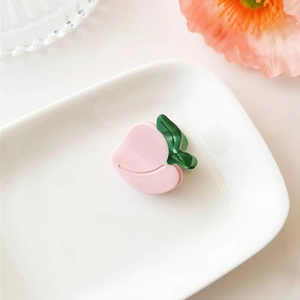 Close-up of pink peach hair claw made of acetate on a white decorative porcelain tray