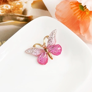 Détail d'une pince à cheveux papillon dégradé rose avec cadre doré et texture