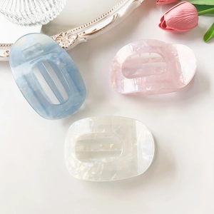 Detail view of acetate claw clips in marble blue, pink, and white on a white backdrop