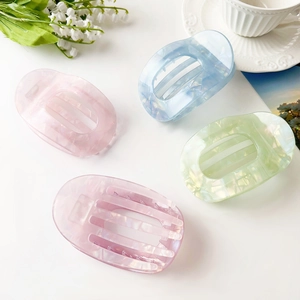 Set of four pastel acetate hair claws in pink blue green and purple on white desk