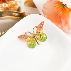 Détail de la pince papillon en émail dégradé avec texture d'écailles sur plateau