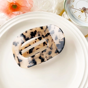 Detail of tortoiseshell patterned acetate hair claw clip on white ceramic plate