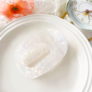 Macro view of pearlescent white acetate hair claw clip with holographic shell texture