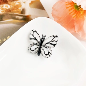 Vue macro d'une broche papillon noir et blanc avec texture d'aile en émail fin