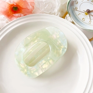 Detailed macro view of mint green marble acetate hair claw clip on a white ceramic plate