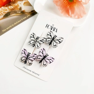 Vue détaillée de barrettes papillon en dégradé violet et noir sur leur support de présentation