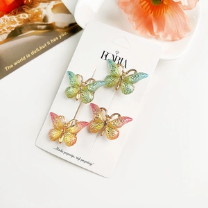 Détail de pinces à cheveux papillon dégradées avec bords dorés sur une carte de support