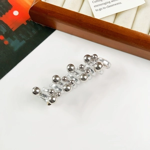 Detail of silver bead hair clip with transparent spiral base on a white aesthetic background