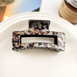 Macro detail of rectangle leopard print hair claw clip with marble texture on ceramic tray