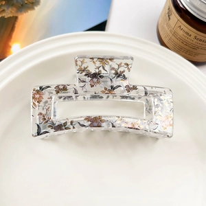 Detailed close-up of a hollow rectangular hair claw with vintage floral prints on a tray