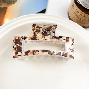 Detail view of square marble pattern hair claw clip on a white plate with aesthetic decor