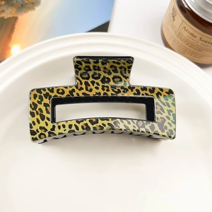 Macro shot of rectangular hollow hair claw clip with glossy yellow leopard print