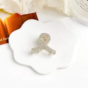 Dettaglio dell'elegante pinza per capelli dorata con strass scintillanti e design a nastro