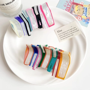 Detail of book-shaped acrylic hair clips in vibrant candy colors displayed on a white plate