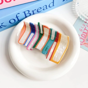 Detail of colorful acrylic book-shaped hair claw clip with pearlescent texture and finish