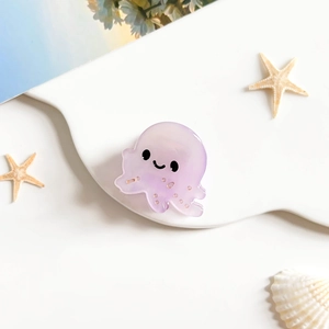 Détail d'une pince à cheveux en acétate violette en forme de méduse avec un visage souriant