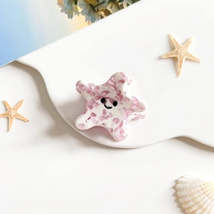 Gros plan d'une pince à cheveux étoile de mer rose avec motif smiley joyeux