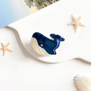 Détail de la pince à cheveux en acétate en forme de baleine bleue et blanche