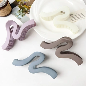 Detailed view of matte wavy shark hair clips in four Morandi colors on a white surface