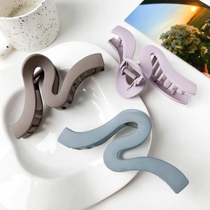 Detail showing wave-shaped matte hair claws in coffee, lavender, and grey blue colors