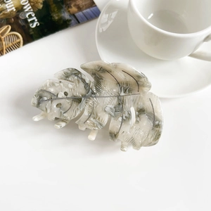 Détail d'une pince à cheveux en forme de feuille d'acétate avec un motif marbré chic