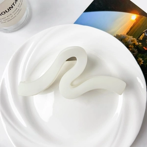 Close-up of matte cream wavy shark hair clip on a white ceramic plate for thick hair
