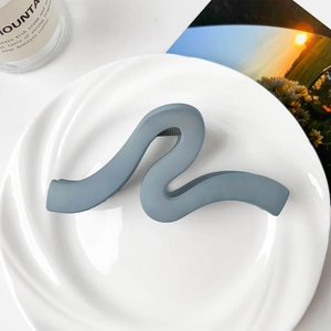 Detail view of large matte blue wavy hair claw clip on a decorative ceramic tray