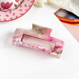 Detailed top view of a marble pink resin rectangle hair claw clip on a white background