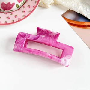 Macro detail of a large rectangular marble hair claw clip in pink and white acetate