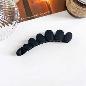 Vue rapprochée de la pince à cheveux banane noire mate sur table blanche avec accessoires