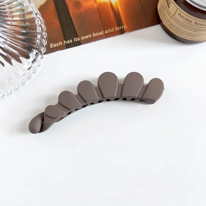 Gros plan d'une barrette banane marron mat festonnée sur un fond esthétique minimaliste