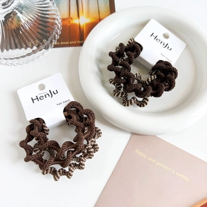 Detailed view of elastic brown and striped spiral hair bands on a white porcelain dish