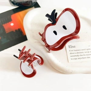 Detail view of large and small red apple hair claws on a ceramic plate