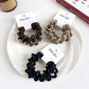 Detailed view of high elasticity ribbed hair ties in coffee tones on a white plate