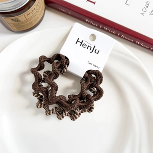 Detail of premium ribbed hair bands in brown tones on a white porcelain dish