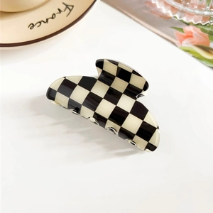 Detail shot of a black and white checkered hair claw clip on a stylish ceramic tray