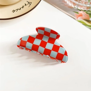 Detail view of a semi-circle red and white checkered hair claw clip on a tray