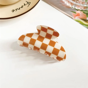 Detail of checkered orange and white hair claw clip with smooth resin surface finish
