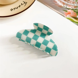Detail of mint green and white checkered PVC hair claw clip on a stylish ceramic plate