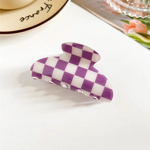 Detailed close-up of a purple and white checkered hair claw clip on a decorative plate