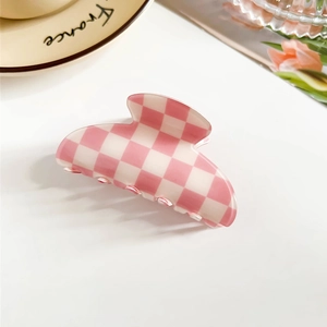 Close-up of pink and white checkered PVC hair claw clip on elegant French style table