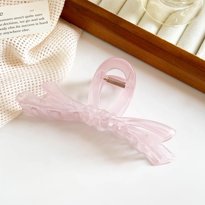 Détail d'une pince à cheveux papillon rose translucide avec ressort en métal doré
