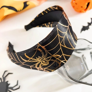 Détail du serre-tête d'Halloween noir avec motifs d'araignées et toiles dorées sur fond