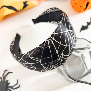 Gros plan du serre-tête noir Halloween avec motif toile d'araignée blanche sur verre